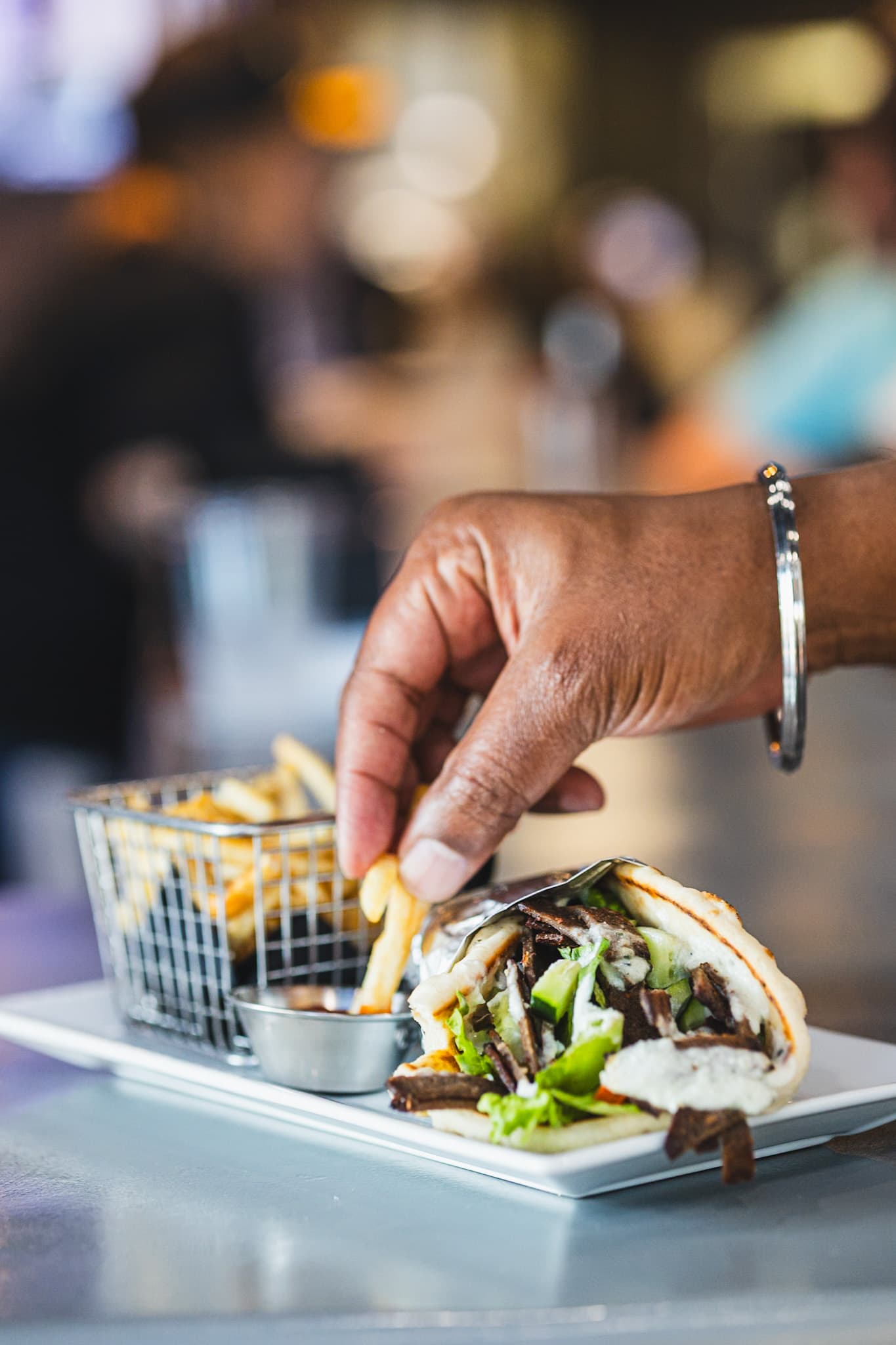 Guest dipping a fry with gyro and fries at The Owner's Box